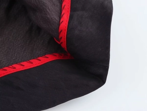 Détail du tissu de robe noir avec bordure rouge et surpiqûres décoratives en zigzag