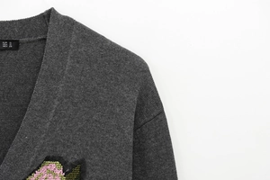 Détail de la broderie florale sur un gilet en maille épaisse grise à col en V pour femme