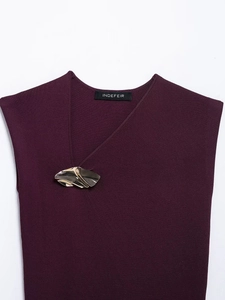 Dettaglio top in maglia bordeaux con scollo asimmetrico e fibbia in metallo dorato