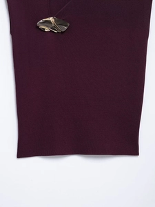 Dettaglio della maglia in maglia viola scuro con fibbia in metallo dorato dal design unico