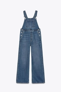 Detail of blue denim overalls showing front pocket, buckle straps and side buttons