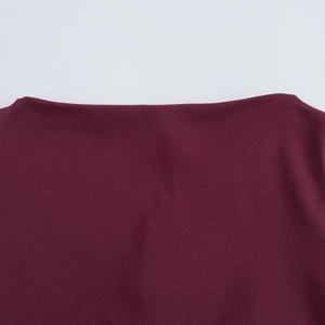 Detailed close-up of burgundy knit fabric and clean neckline stitching on dress