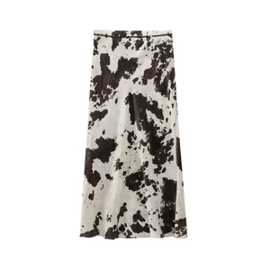 Détail d'une jupe midi trapèze avec imprimé vache noir et blanc et fine ceinture noire
