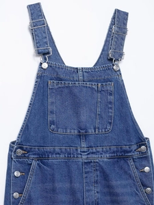 Detail of adjustable metal buckles and chest pocket on blue denim overalls for women