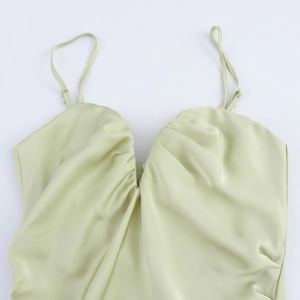 Détail d'un haut en satin vert clair avec fines bretelles et plis en décolleté V