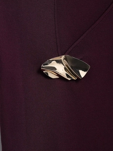 Dettaglio della maglia a coste bordeaux con un bottone metallico dorato lucido irregolare