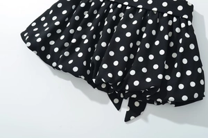 Close-up of ruffled hem and polka dot print fabric with pleated texture and tie detail