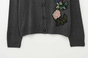 Détail d'un cardigan gris foncé avec broderie florale 3D colorée et boutons foncés