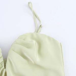 Détail des fines bretelles réglables et du buste froncé sur une robe midi en satin vert