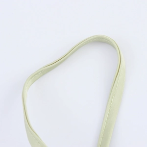 Détail de la bretelle en satin vert clair avec des coutures précises et texture soyeuse