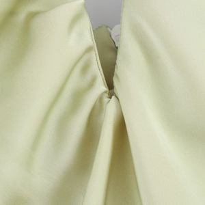 Détail d'une robe midi en satin vert pistache montrant le décolleté et la texture soyeuse
