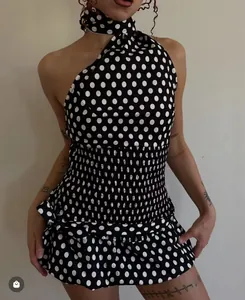 Detailed view of the smocked waist and ruffle hem on a black polka dot neck-tie outfit