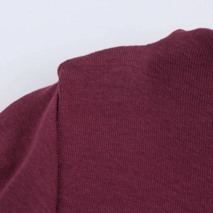 Detailed close-up of stitching on deep burgundy knit dress with high-density fabric texture