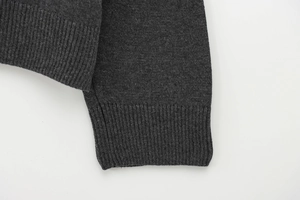 Gros plan d'un pull en maille gris foncé montrant les poignets côtelés et la texture