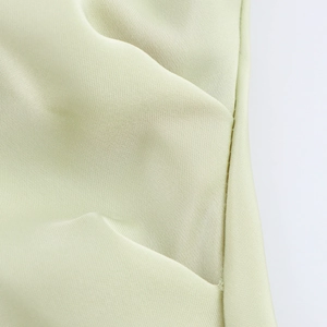 Détail d'une robe en satin vert clair montrant les coutures de qualité et la texture du tissu