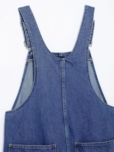 Detail of denim overalls showing adjustable metal buckles and reinforced stitching