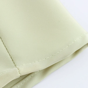 Détail d'une robe midi satin vert clair montrant le tissage sergé et les coutures soignées