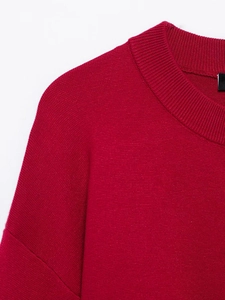 Détail d'un pull en maille rouge avec col rond côtelé et texture de tissage fine