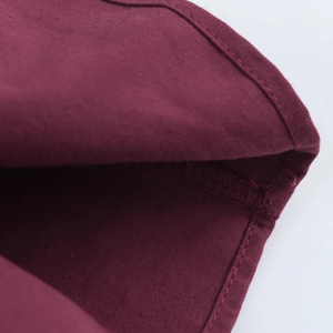Macro view of the burgundy fabric showing fine rolled edge sewing and overlock stitches