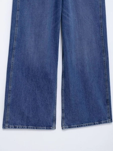 Detail of wide-leg denim overalls featuring yellow contrast stitching and twill fabric