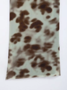 Detail shot of light green leopard print fabric with precise overlock stitching edge