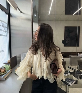 Close-up of layered ruffles and delicate chiffon texture on elegant beige blouse