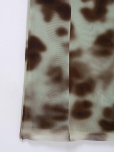 Detailed close-up of brown and light green tie-dye mesh fabric with sheer texture