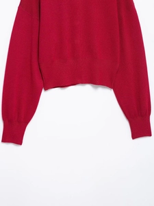 Détail d'un pull en maille rouge foncé montrant les poignets et l'ourlet côtelés