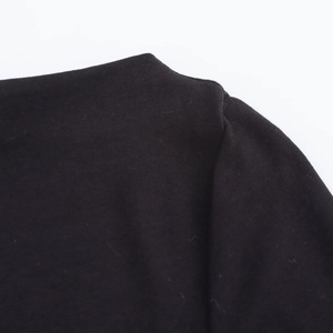 Detail view of smooth black knit fabric texture and shoulder stitching on a mini dress