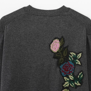 Gros plan sur un cardigan en maille gris anthracite avec broderies de roses colorées