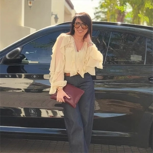 Detail of a beige ruffle layered V-neck sleeveless top paired with blue straight jeans