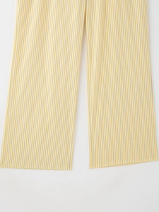 Détail du pantalon à rayures jaunes et blanches avec coupe large et plis fluides