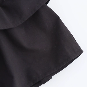 Detailed macro view of the ruffled hem on this black pleated dress for women
