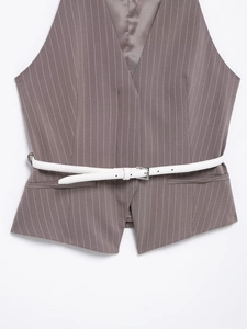 Dettaglio del gilet gessato con scollo a V profondo e cintura sottile bianca con fibbia