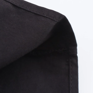 Detailed close-up of the fine flat-seam stitching on black pleated dress fabric