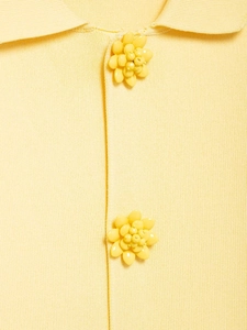 Close-up of yellow knit cardigan featuring detailed 3D floral buttons and lapel textures