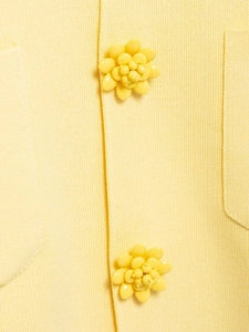 Close-up of fine knit light yellow cardigan featuring intricate floral button detail