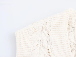 Gros plan sur le gilet en coton blanc cassé avec torsades et bordure en maille côtelée