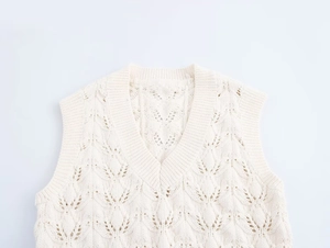 Détail macro du gilet en coton blanc cassé avec motifs de feuilles ajourées et torsades