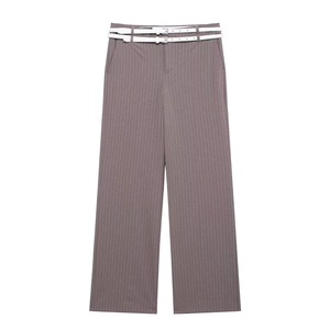 Dettaglio dei pantaloni grigi gessati con eleganti doppie cinture bianche e fibbie