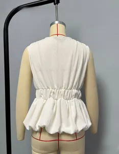 Detail of white sleeveless top with textured pleated fabric and ruffled peplum hemline