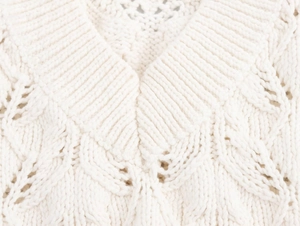 Détail de la veste en maille de coton blanc crème avec col en V et motifs torsadés
