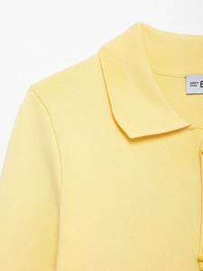 Close-up of a pale yellow knit polo cardigan featuring a neat collar and matching buttons