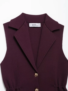 Détail du gilet en tricot bordeaux avec col à revers et boutons dorés métalliques