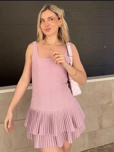 Detail view of the pink sleeveless mini dress featuring a pleated layered hemline