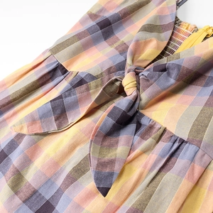 Close-up of multi-color plaid dress featuring front bow tie and side zipper detail
