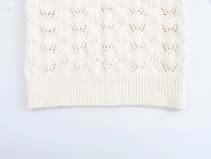 Gros plan sur la texture florale pointelle et l'ourlet côtelé du gilet en maille crème