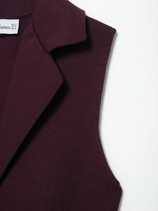Détail du gilet en maille violet foncé avec col classique et étiquette de taille interne