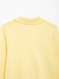Detail of light yellow knit sweater showing high neckline and fine ribbed texture