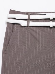 Dettaglio pantaloni marroni a righe sottili con doppie cinture bianche effetto coccodrillo